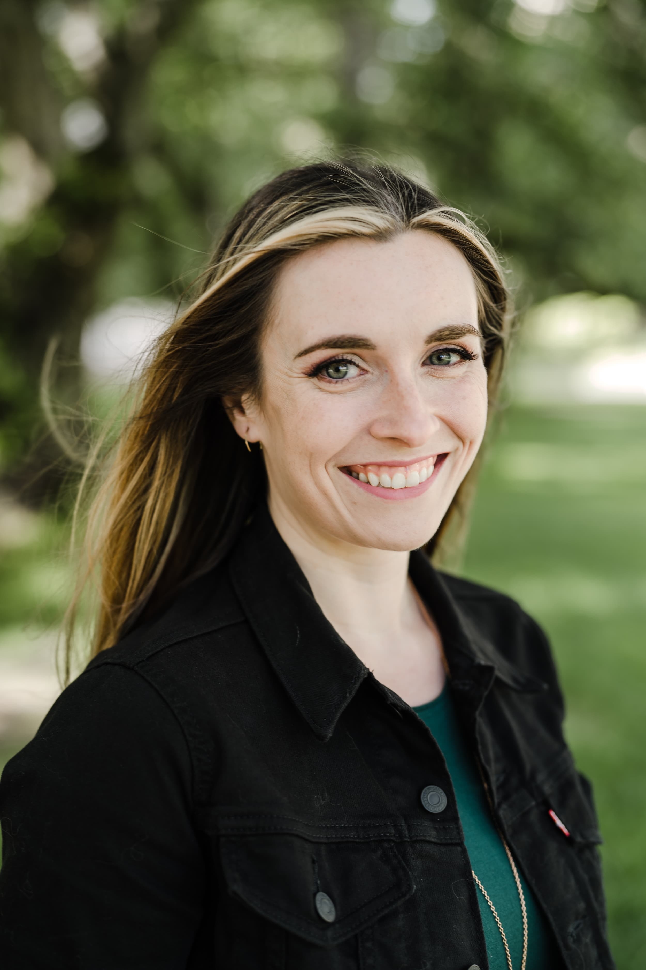 Megan Brown, smiling outdoors in a black denim jacket